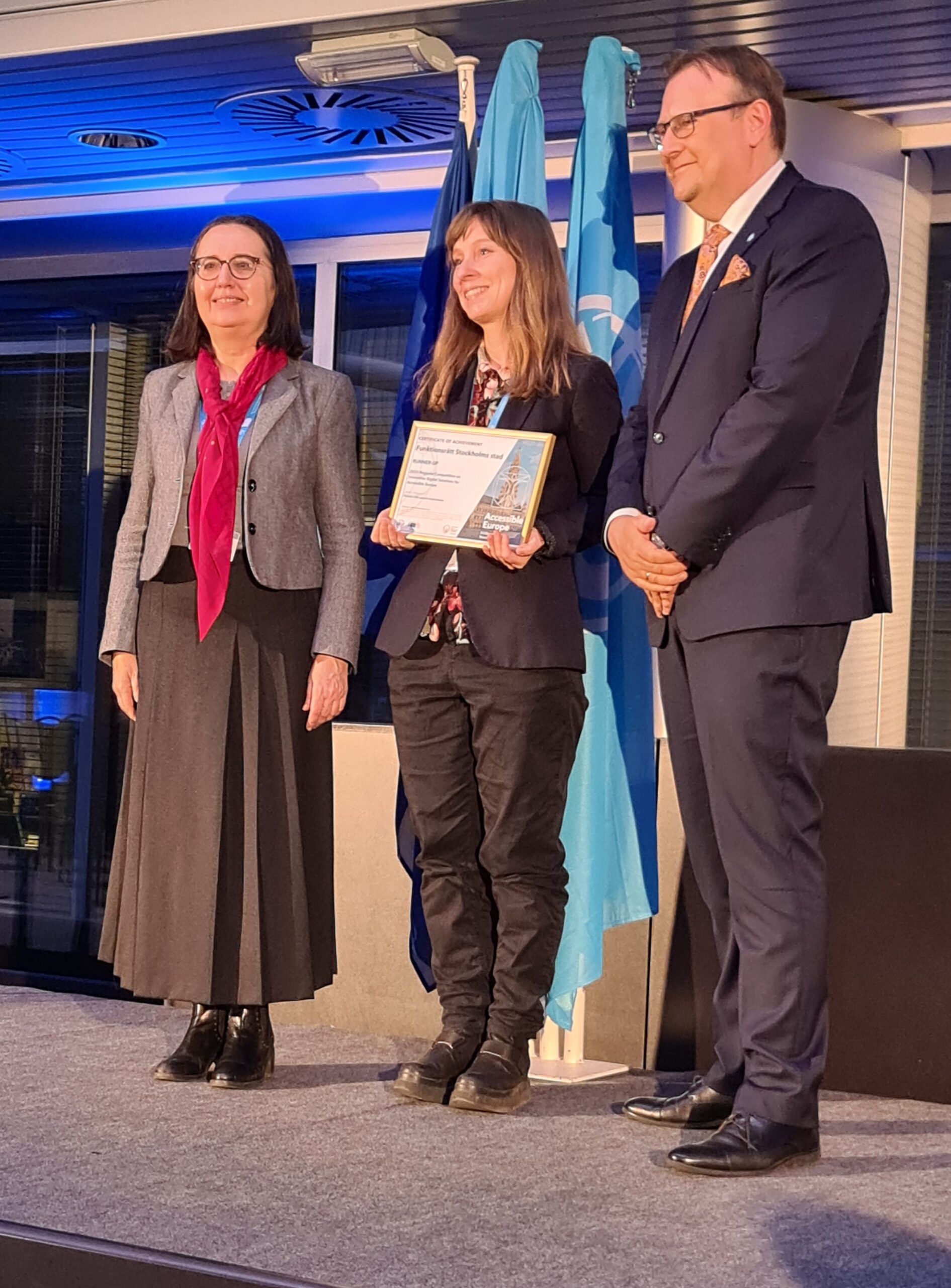 Bild Marian Bergroth håller ett certifikat mellan arrangörerna från EU-kommissionen och ITU